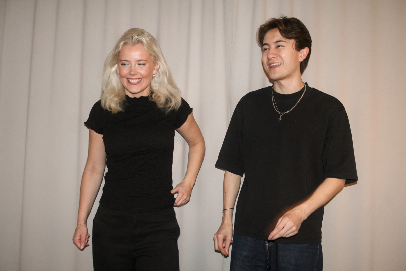 Frida Erlandsson och Isak Havborg skrattar framför ett ljust draperi